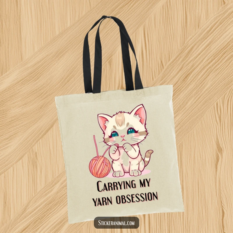 Funny curious kitten batting playfully at a dangling yarn ball, depicted on a durable and adorable tote bag.